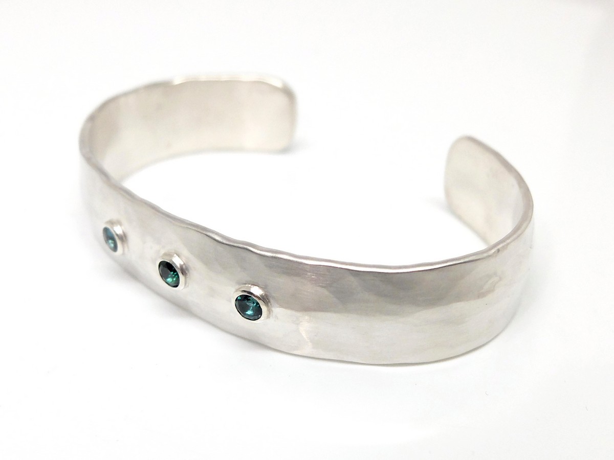 Handgefertigter Armschmuck aus Silber. Ein offener, breiter und ovaler Armreif, geschmiedet. Auf der Vorderseite mittig drei blaugrüne Turmaline.